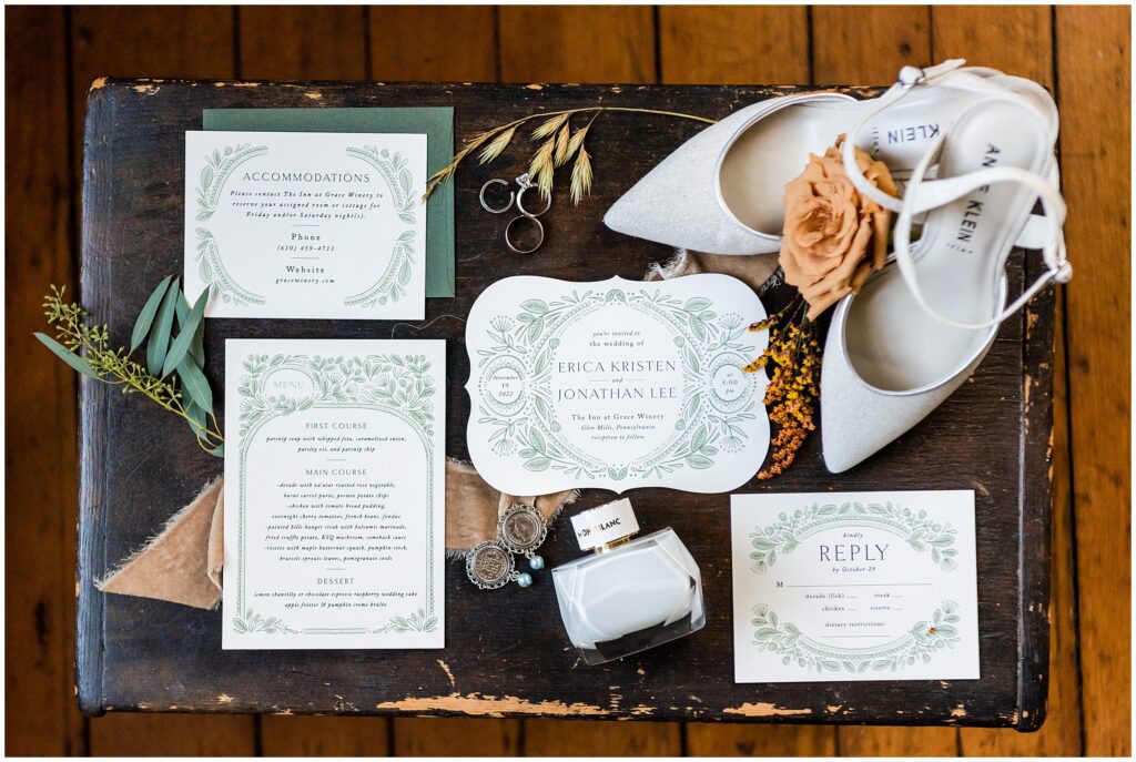 white and green wedding invitation styled with wedding rings, perfume, wedding shoes and other accessories