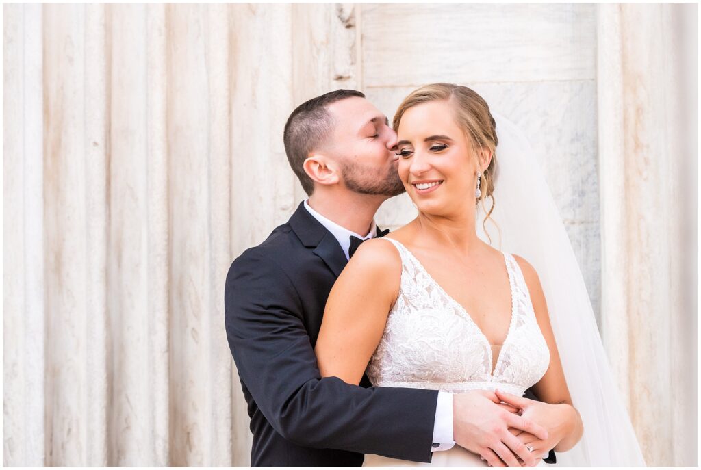 Groom embraces and kisses his bride