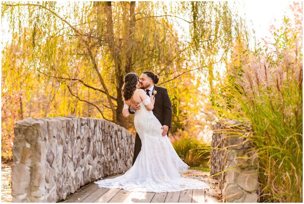 Couple kisses on the bridge at Prophecy Creek surrounded by fall foliage