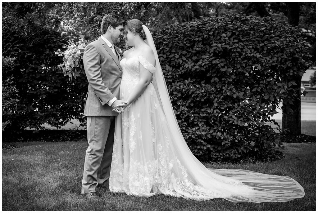 Black and white wedding portrait of bride and groom touching heads together and holding hands | Ashley Gerrity Photography