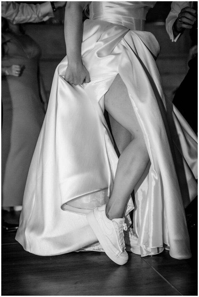 Black and white portrait of bride showing off her Nike sneakers on the dance floor of her Greek wedding reception at Union Trust | Ashley Gerrity Photography