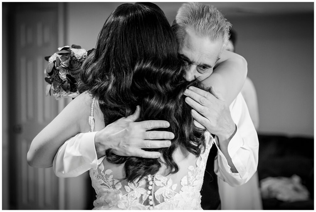 Black and white wedding portrait of bride hugging her father after their first look | Ashley Gerrity Photography