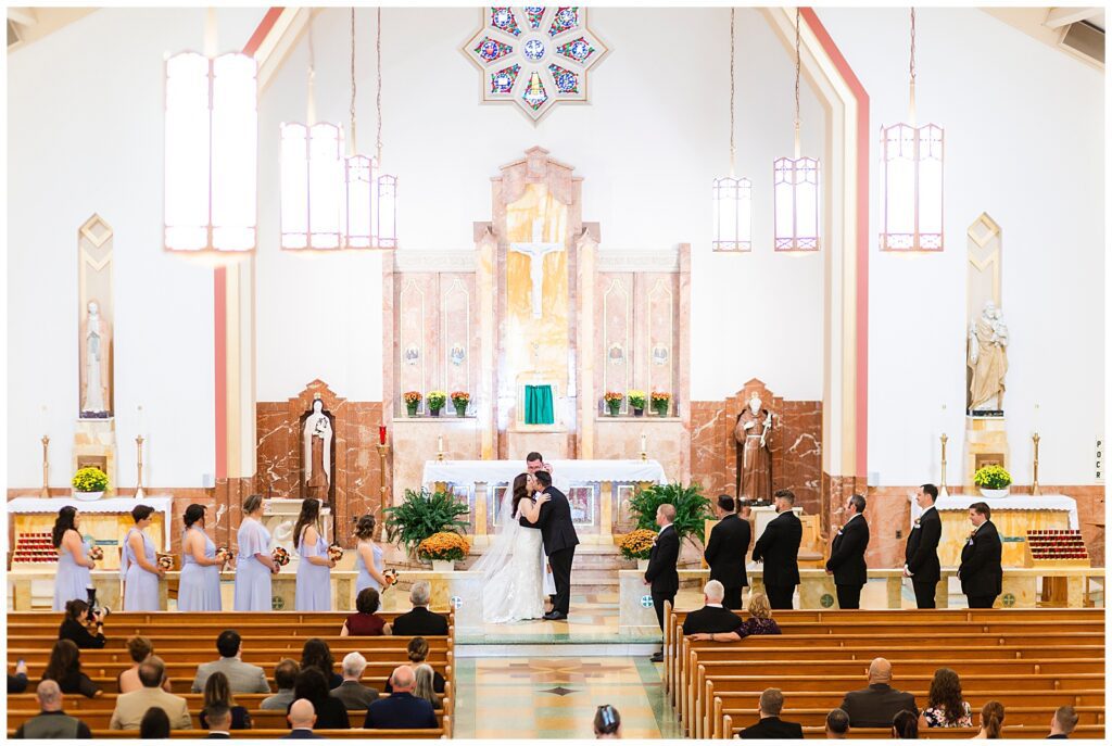 Bride and groom first kiss on the altar of St. Cecilia church during traditional Catholic wedding ceremony | Ashley Gerrity Photography