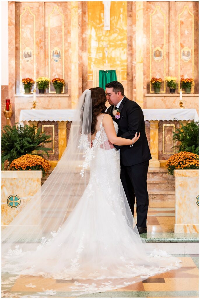 Wedding portrait of bride and groom going in for a kiss at the altar after St. Cecilia wedding ceremony | Ashley Gerrity Photography