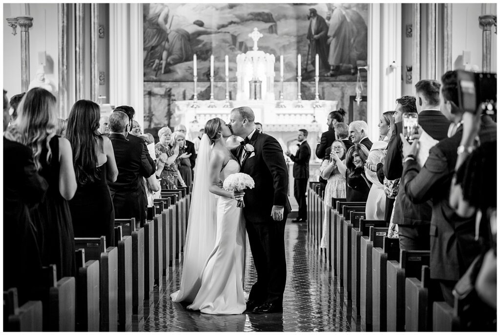 Bride & Groom share their first married kiss as they walk down the aisle of a catholic church