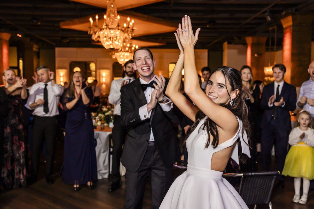 Bride clapping her hands over her head while dancing as her groom and wedding guests surround her clapping at Cescaphe's Tendenza