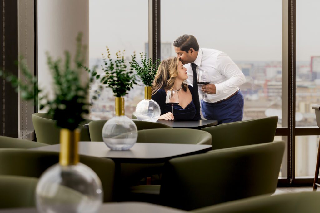 Portrait of a woman & Man in a high rise lounge sharing a glass of wine