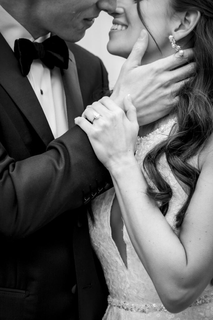 Close up black & white detail of bride holding a groom's wrist as he pulls her in for a kiss