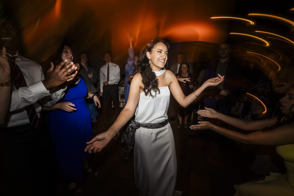 Bride dancing in the middle of a dancefloor with blurring lights and people around her