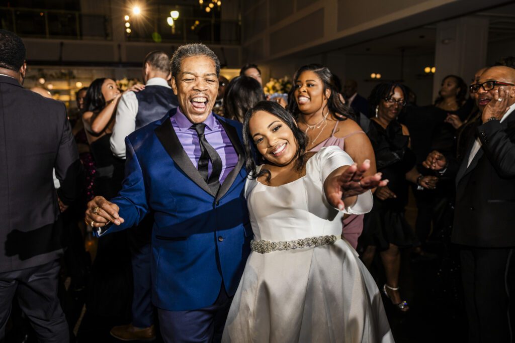 Bride dances joyfully with an older man during a wedding reception